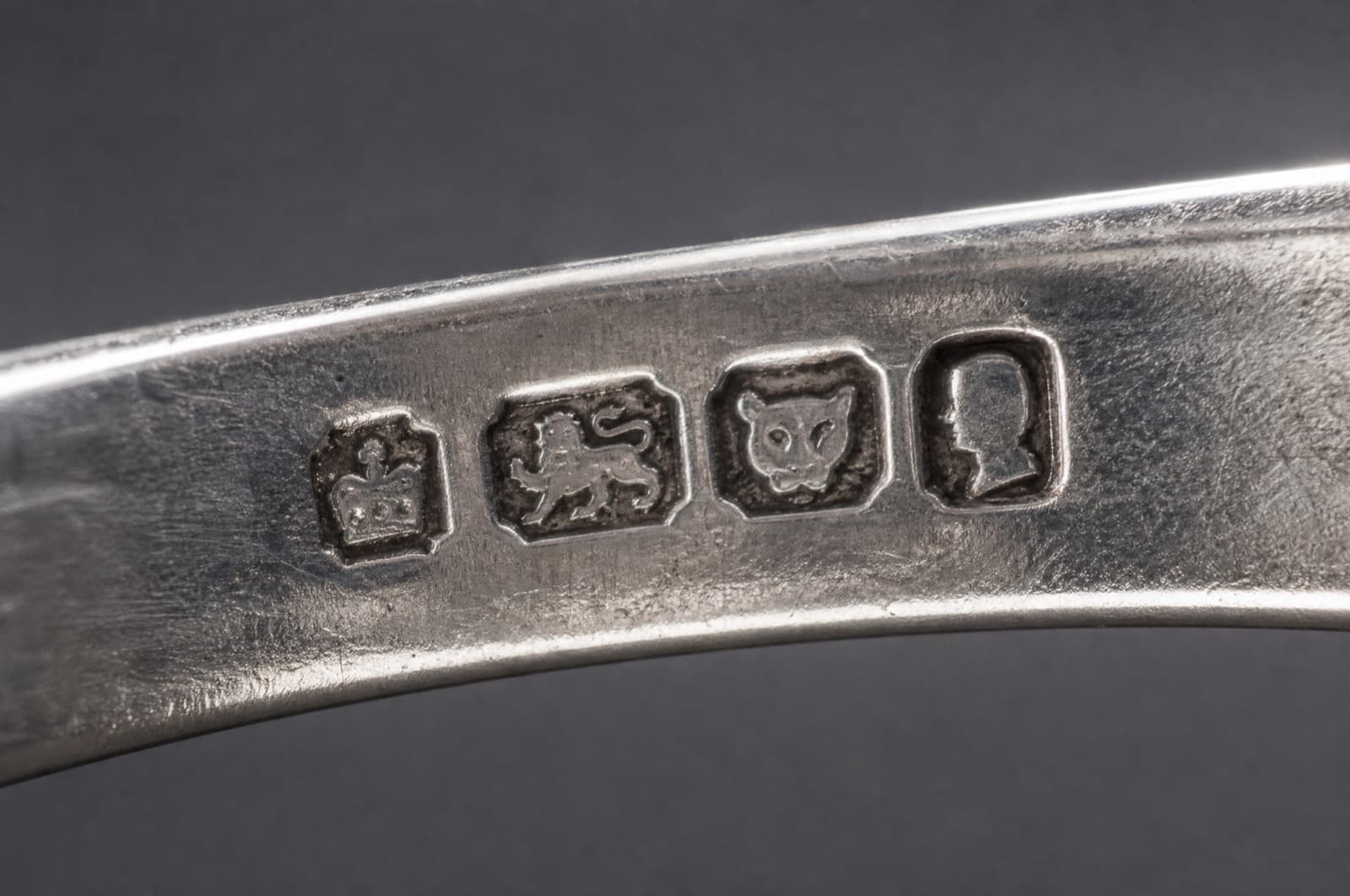 A row of struck hallmark punch marks impressed into the inner surface of a silver band, magnified